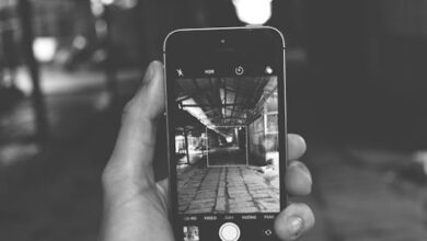 A smartphone held in hand displays a monochrome photo of an indoor setting.