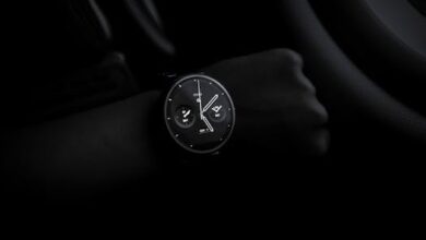 A sleek Moto 360 smartwatch showing time on a wrist in a dimly lit setting, emphasizing its modern design and technology.