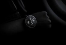 A sleek Moto 360 smartwatch showing time on a wrist in a dimly lit setting, emphasizing its modern design and technology.